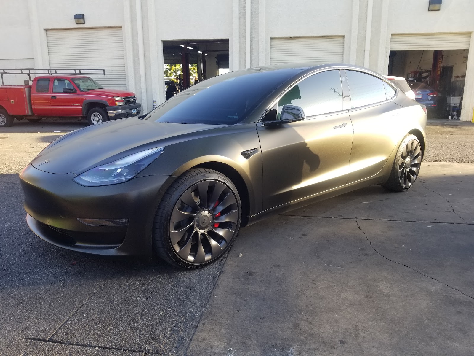 Satin black wrapped Tesla Model 3 with black wheels at the shop